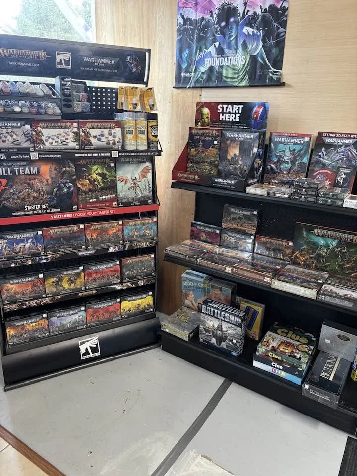 The Warhammer and board game rack inside Roc Collectibles, with 40K and Age of Sigmar starter sets and Citadel paints